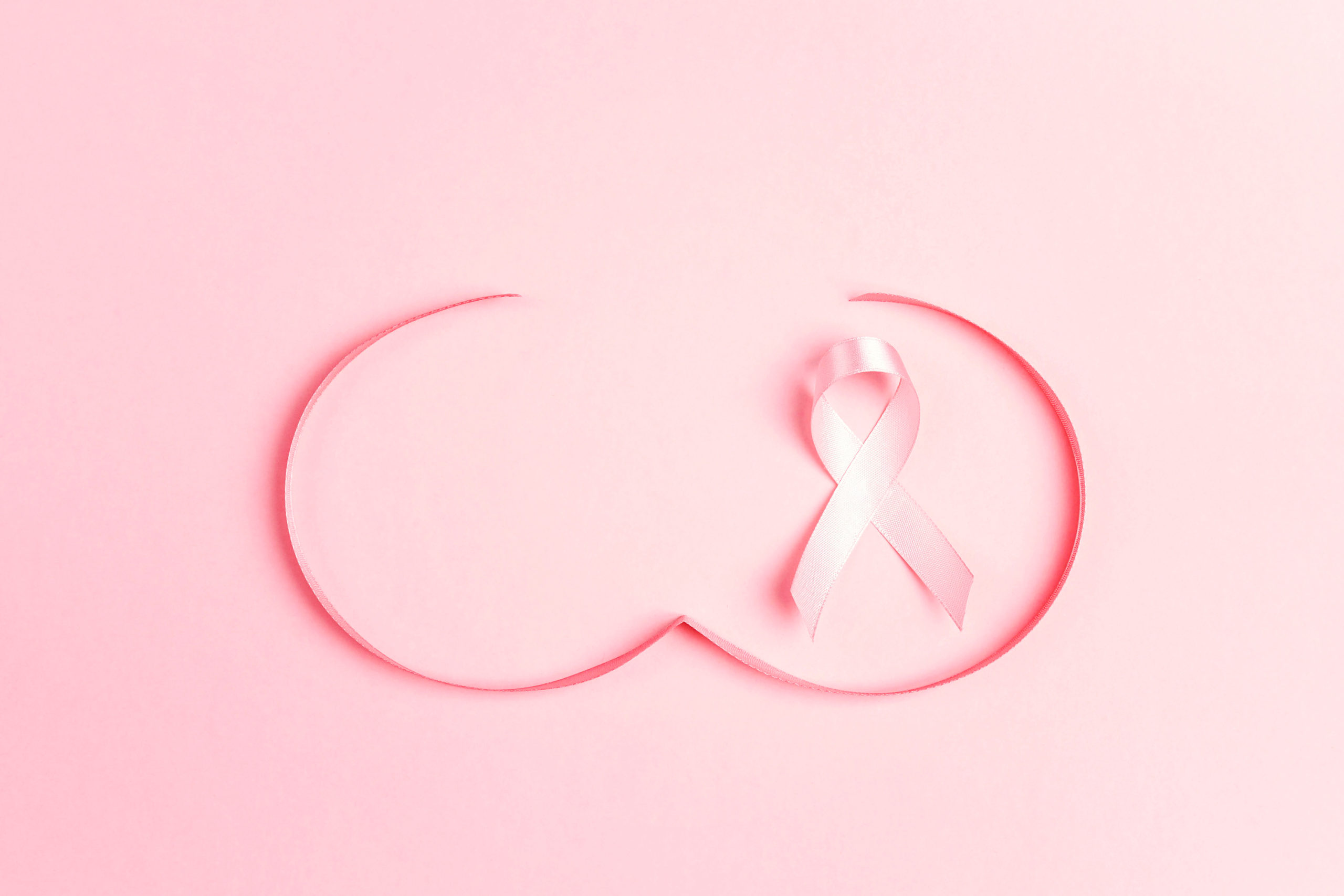 Pink ribbon with breast shape symbol on pink background.  Breast cancer awareness symbol. October awareness month campaign.