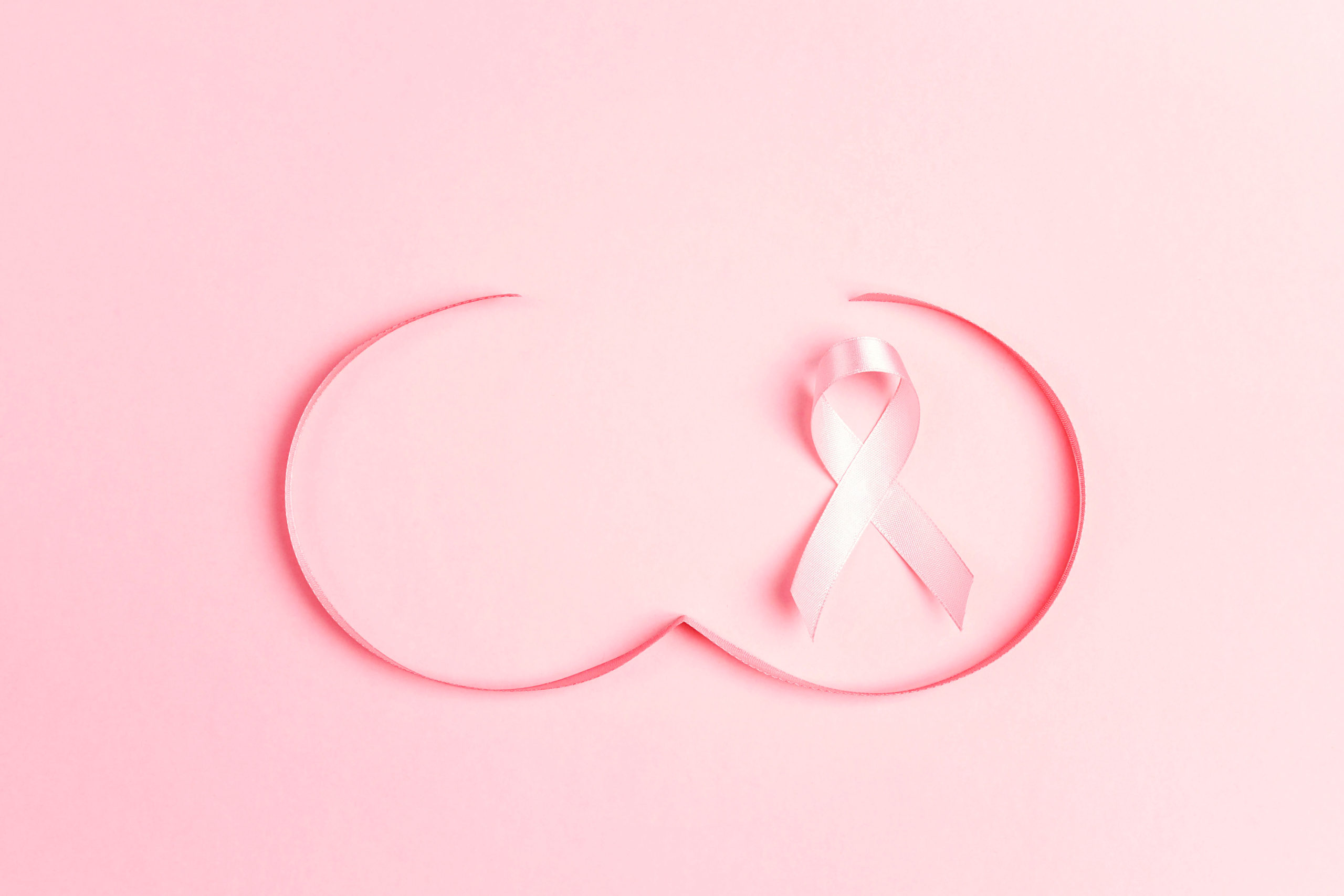 Pink ribbon with breast shape symbol on pink background. Breast cancer awareness symbol. October awareness month campaign.